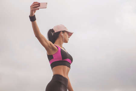 Brunette slim adult sexy fit sporty caucasian woman in sportswear on a european city streets in morning do exercises (workout), stretch her legs and butt. Copy spaceの写真素材