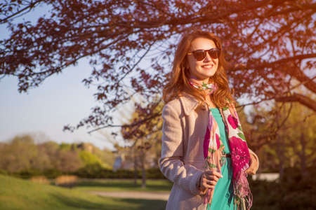 Cute ordinary caucasian brunette woman in casual outfit walking at the nature park. Cold spring...