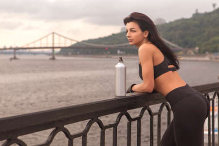 Brunette slim adult sexy fit sporty caucasian woman in sportswear on a european city streets in morning do exercises (workout). Copy spaceの写真素材