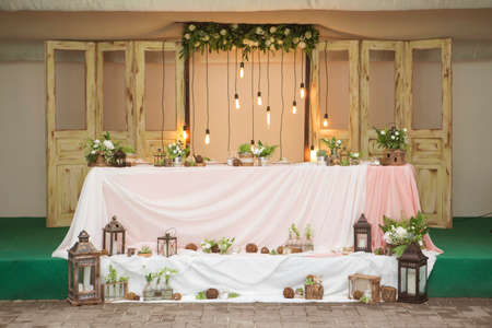 Simple but luxury rich table setting for a wedding celebration in nice cozy restaurant. Wineglasses, plates and bouquet of summer seasonal flowers on a table. Sunlight from a window. Copy spaceの写真素材