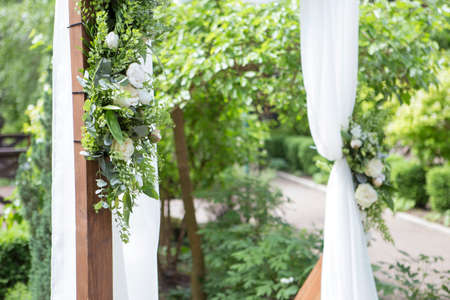 Wedding arch decorated with eustoma roses flowers on a wedding ceremony. Soft day light, outdoor in gardenの写真素材