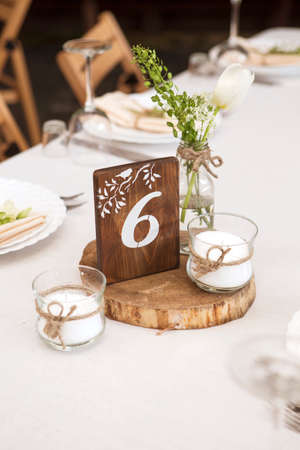 Simple but luxury rich table setting for a wedding celebration in nice cozy restaurant. Wineglasses, plates and bouquet of summer seasonal flowers on a table. Sunlight from a window. Copy spaceの写真素材