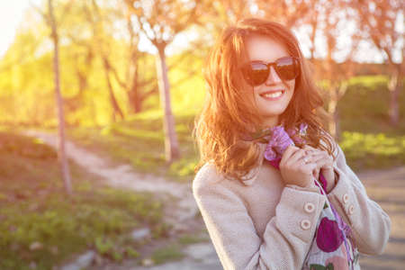 Cute ordinary caucasian brunette woman in casual outfit walking at the nature park wearing...