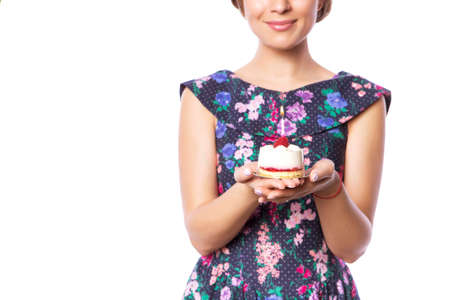 Brunette pretty beautiful caucasian woman in blue festive dress blowing candle on a birthday party cupcake. Isolated white backgroundの写真素材