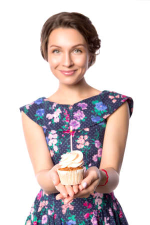 Brunette pretty beautiful caucasian woman in blue festive dress blowing candle on a birthday party cupcake. Isolated white backgroundの写真素材