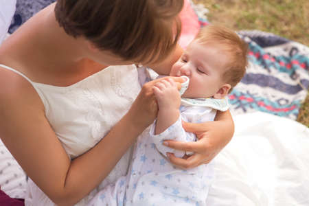Little newborn infant baby boy kid on a plaid in park. Summer sunset. Copy space