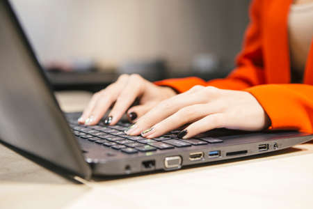 Business woman sitting in her modern office in luxury red jacket. Neutral interior with dim led...