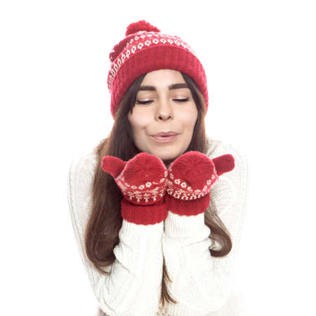 Cute teenage girl with long dark hair standing on a white background in white sweater and red santa...