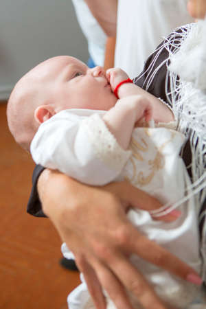 Godfather (caucasian young man) holding little infant kid in baptism (christening) ceremony in churchの写真素材