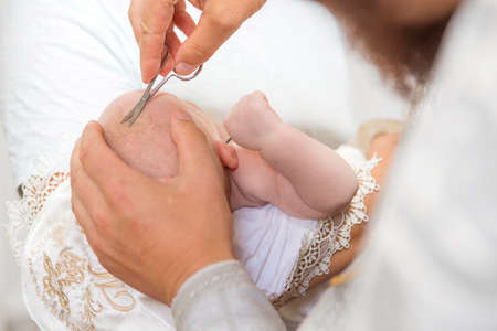 Mother (caucasian young woman) holding little infant kid in baptism (christening) ceremony in church