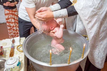 Abbe blessing a little infant kid in baptism (christening) ceremony in church, anointing him