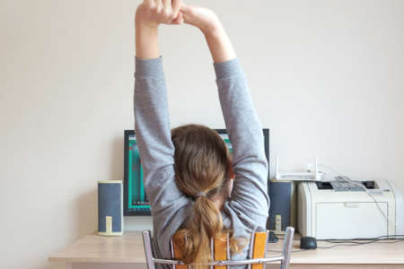 distance learning, tired girl stretches at the tableの写真素材