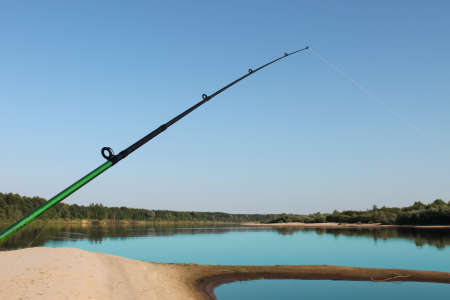 a spinning reel against the background of a riverの写真素材