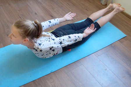 girl doing physical exercises in the room on a sports carpet
