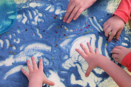 sand therapy, child's hands are painted on a white table with blue sandの写真素材