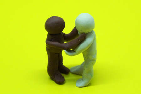 figures of white and black people, symbolizing the friendship of peoples, love, acceptance, anti-racism on the yellow backgroundの写真素材
