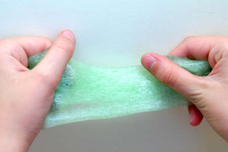 close-up of children's hands stretching green slimeの写真素材