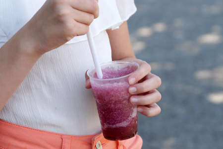 girl holding fruit cocktail with a straw in the park on a sunny day.の写真素材