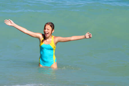 girl with hands up smiling at sea, copy spaceの写真素材