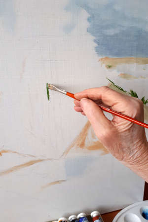 hand of an elderly woman with a brush paint a pictureの写真素材