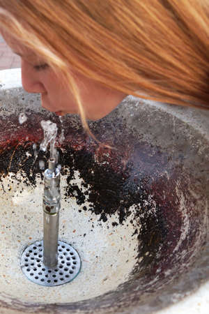 girl drinks water from a fountain close-up
