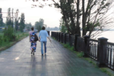 young couple walking along the embankment after rain, back viewの写真素材