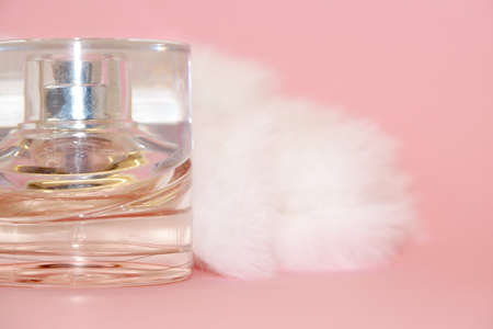 perfume bottle and white fur on a pink background close-upの写真素材