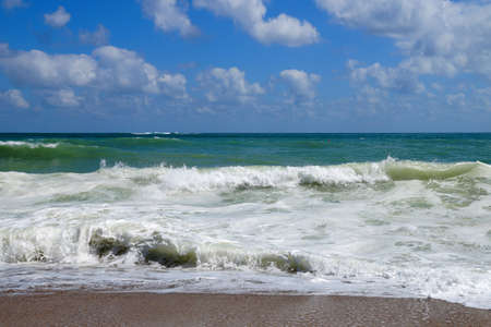 big white waves hitting the sea shore on the sunny day
