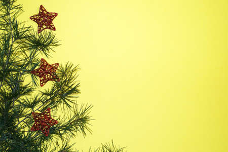 coniferous branches and Christmas tree decorations on a New Year's yellow background, copy space.