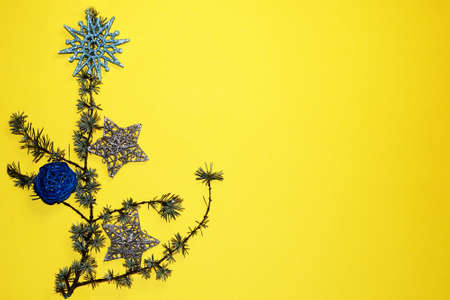 coniferous branches and Christmas tree decorations on a New Year's yellow background, copy space.の写真素材