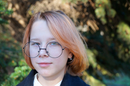 portrait of smiling teenage girl with blond hair wearing glasses.