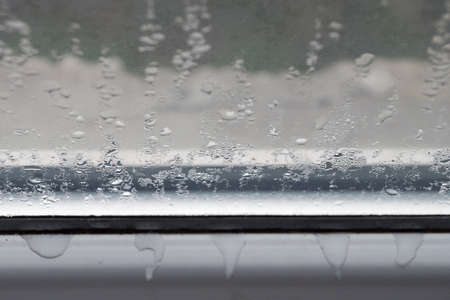 wet misted glass close-up, condensation on the plastic window frame.
