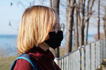 teenage girl in a medical mask in an autumn on the sea.の写真素材