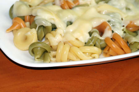 pasta with melted cheese on a white plate close up