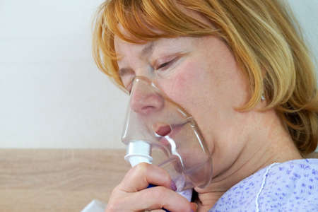 sick middle-aged woman breathing with inhaler portrait