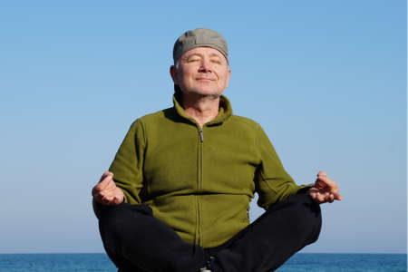 adult man meditates with a smile on the background of the sea horizon.の写真素材