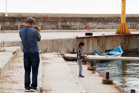 Varna, Bulgaria - November, 15, 2020: father photographs son fishing on the pierのeditorial素材