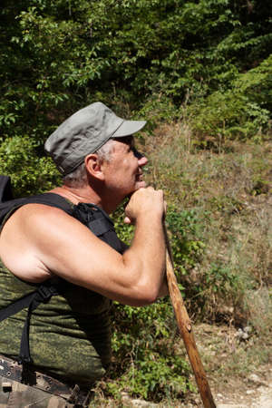 adult smiling man leaning on a stick surveys the surroundings.