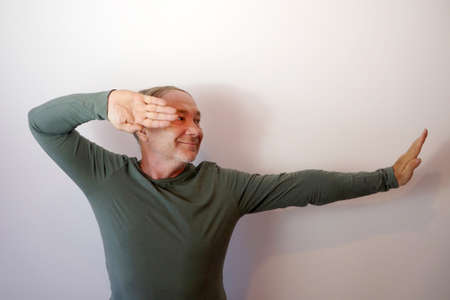 Smiling middle aged man in karate fighting stance on light background.