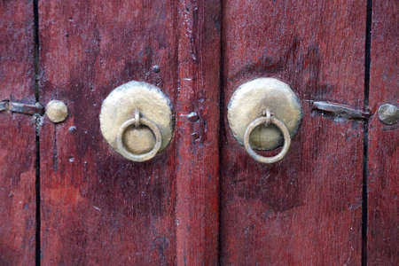 vintage metal knobs with a ring on an old wooden door close-up.