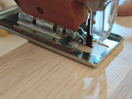 electric jigsaw sawing a board close up.