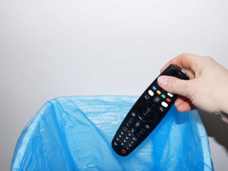 a woman's hand throws the TV remote control into the trash can close-up, copy space