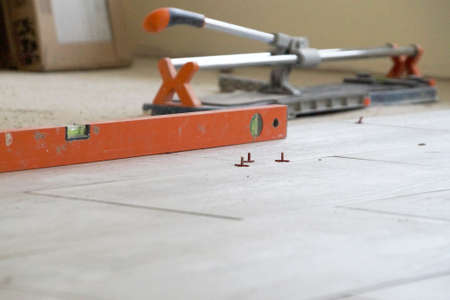 building level and tile cutter on the floor, laying floor tiles.の写真素材