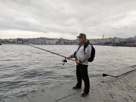 Istanbul, Turkey - November, 25, 2022: a fisherman with a spinning rod on the pier of the Sea of...
