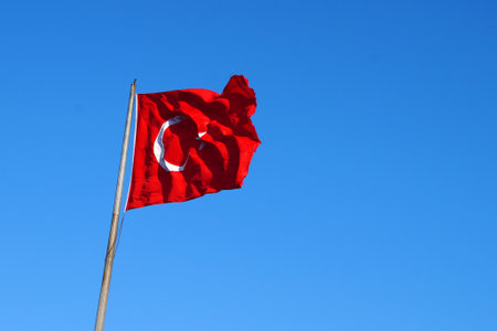Turkish flag waving in the wind against a clear blue sky.