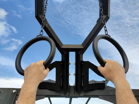 male hands on sports athletic rings against the sky, bottom view.