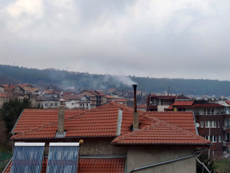 Smoke from a chimney on a tiled roof in a Bulgarian house.の写真素材