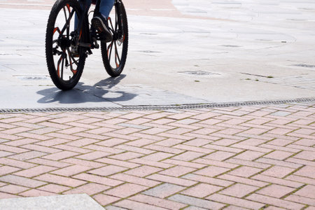 wheels of a riding bicycle with a shadow on the sidewalk, copy spaceの写真素材