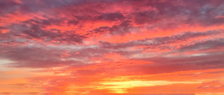 setting sun on a lilac orange cloudy sky for a dramatic sky background.