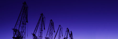 silhouettes of port cranes against the backdrop of a beautiful purple sunset, copy space.